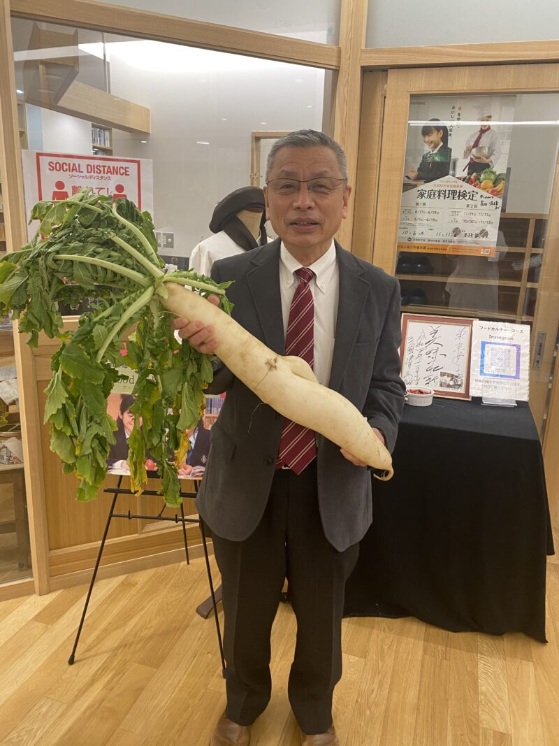 収穫した「練馬大根」をもっての撮影、調理室前後ろには、三國シェフのサイン入り色紙があります。。今回、私、恥ずかしながら写真を載せさせていただきました。「けっこう重たいですね~」
基本的な感染対策を施して、また自分の作ったものだけを自分で食するという「コロナ」の収まらない中での調理実習です。まあ、大人の”試食”については例外として、許可?しました。生徒の皆さん、とびきりおいしかったのですよ!